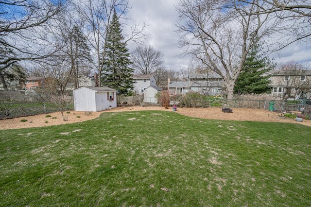 view of yard featuring a fenced backyard, an outbuilding, a storage shed, and a residential view
