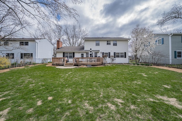 rear view of property with fence, a chimney, a yard, and a deck
