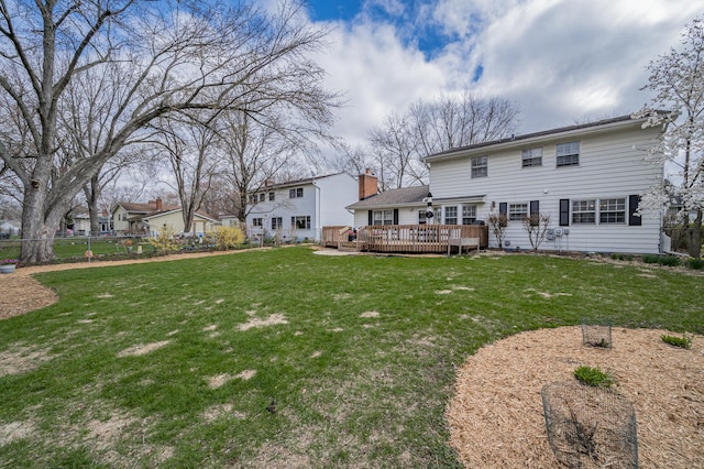 rear view of property featuring a lawn, a wooden deck, and fence