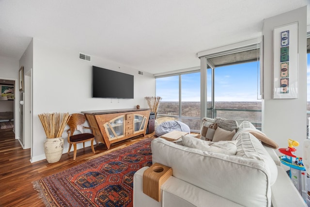 living room with visible vents, floor to ceiling windows, and wood finished floors