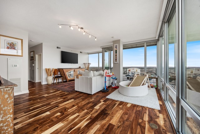 living area featuring visible vents, dark wood-style floors, baseboards, and expansive windows