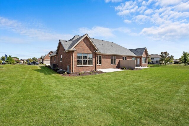 rear view of property featuring a yard, brick siding, and a patio area