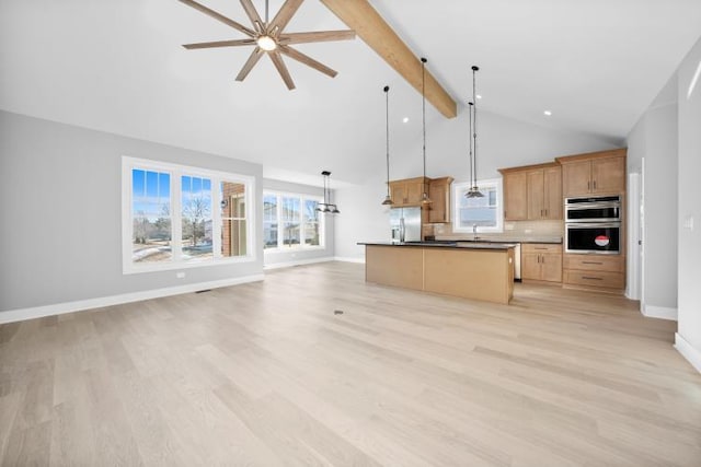 kitchen with beam ceiling, a ceiling fan, open floor plan, appliances with stainless steel finishes, and decorative backsplash