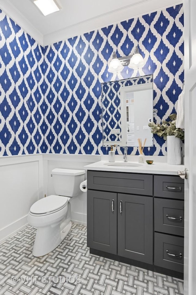 half bathroom with toilet, vanity, and ornamental molding