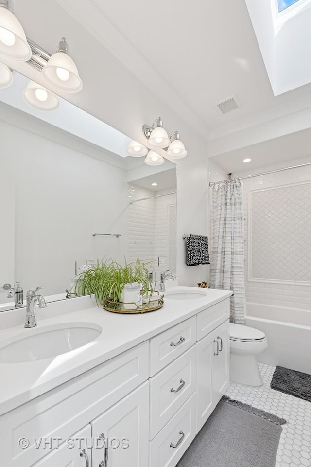 full bathroom featuring toilet, a skylight, a sink, and tile patterned floors