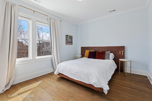 bedroom featuring visible vents, baseboards, ornamental molding, and wood finished floors