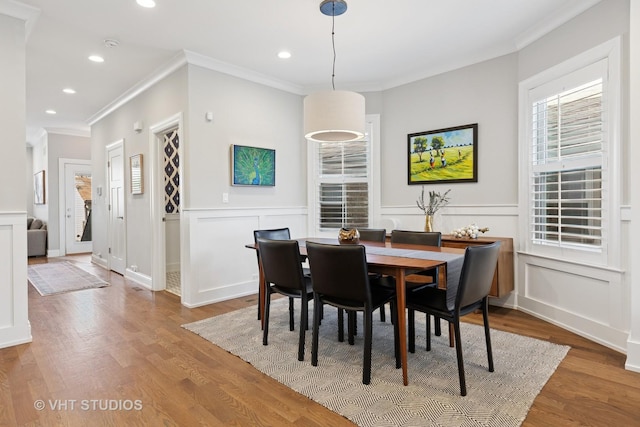 dining space with a decorative wall, ornamental molding, recessed lighting, and wood finished floors