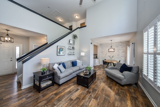 213 Dorset Ave, Oswego, IL 60543 - living room with dark wood-style floors, brick wall, a chandelier, a high ceiling, and stairs