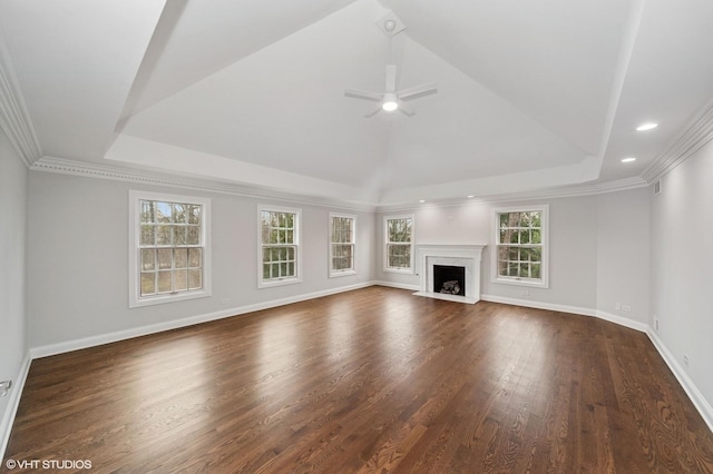 unfurnished living room with a tray ceiling, crown molding, dark wood finished floors, baseboards, and ceiling fan
