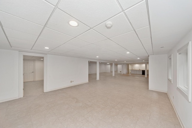 finished below grade area featuring a drop ceiling, baseboards, and recessed lighting