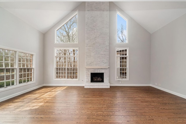unfurnished living room with plenty of natural light, baseboards, a fireplace, and wood finished floors