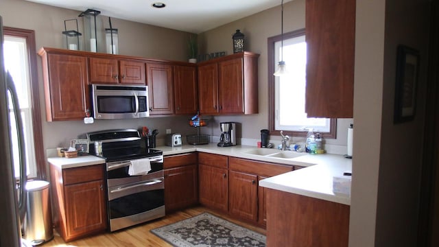 309 W 5th St, Minonk, IL 61760 - kitchen with appliances with stainless steel finishes, a sink, light countertops, light wood-type flooring, and brown cabinets