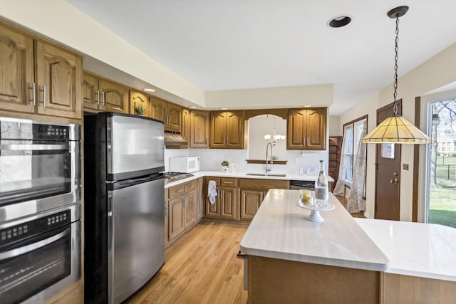 915 N Saratoga Dr, Palatine, IL 60074 - kitchen featuring light countertops, light wood-style floors, appliances with stainless steel finishes, and brown cabinets