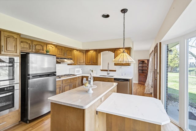 915 N Saratoga Dr, Palatine, IL 60074 - kitchen featuring a center island, a sink, appliances with stainless steel finishes, light wood finished floors, and under cabinet range hood