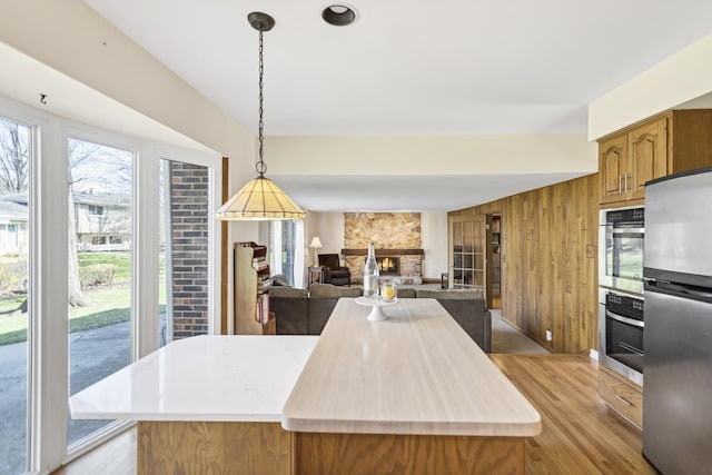 915 N Saratoga Dr, Palatine, IL 60074 - kitchen with stainless steel appliances, light wood-style flooring, brown cabinets, light countertops, and decorative light fixtures