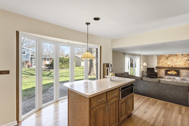 915 N Saratoga Dr, Palatine, IL 60074 - kitchen with light countertops, a warming drawer, light wood-style flooring, and a stone fireplace