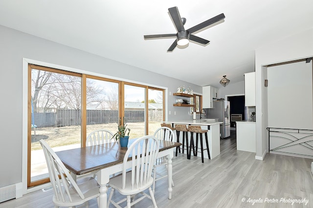 dining space featuring a ceiling fan, lofted ceiling, and light wood-style flooring