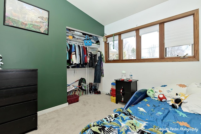 bedroom with a closet, lofted ceiling, baseboards, and carpet