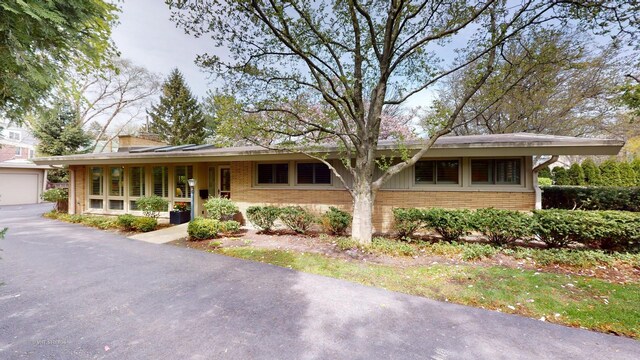 ranch-style home with a garage, a chimney, and brick siding