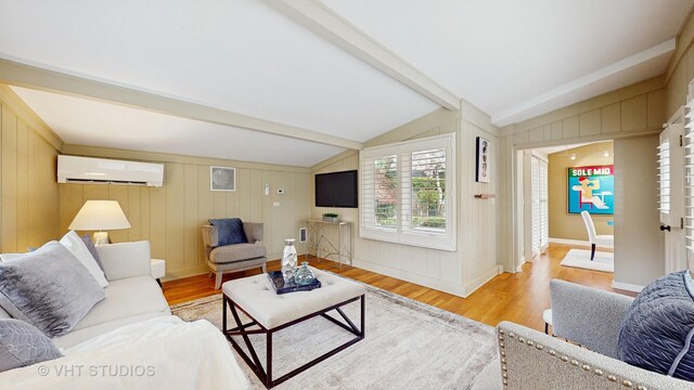 living area featuring visible vents, baseboards, light wood-type flooring, a wall unit AC, and lofted ceiling with beams