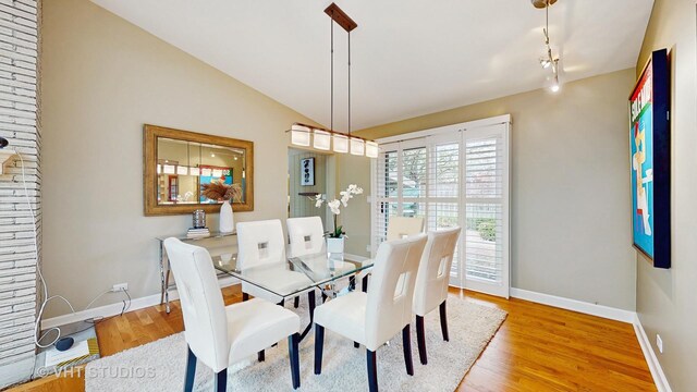 dining area with baseboards, rail lighting, and wood finished floors