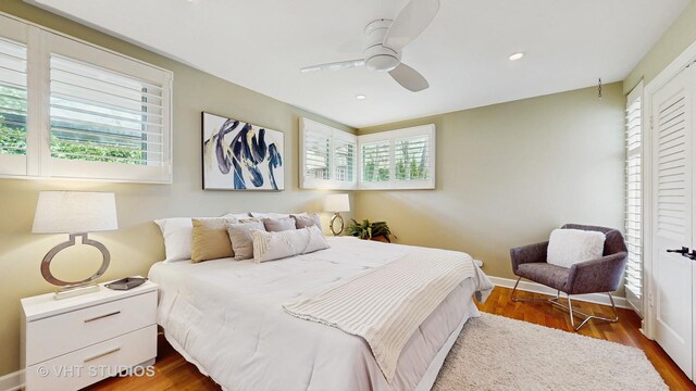 bedroom featuring baseboards, ceiling fan, multiple windows, and wood finished floors