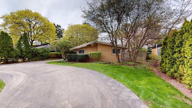 view of side of home with a lawn, brick siding, and fence