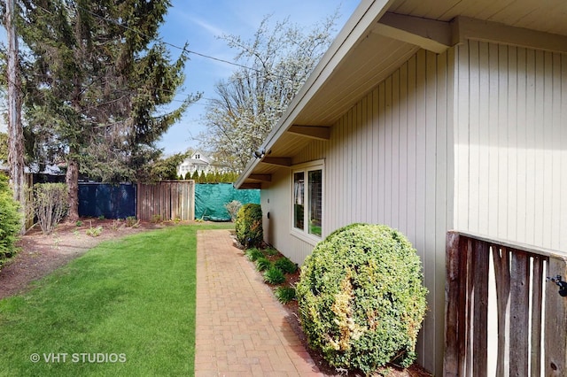 view of side of property featuring fence and a yard