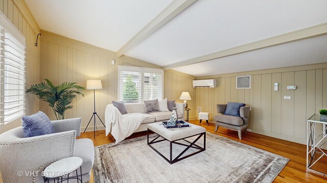 living area featuring vaulted ceiling with beams, a wall unit AC, and wood finished floors