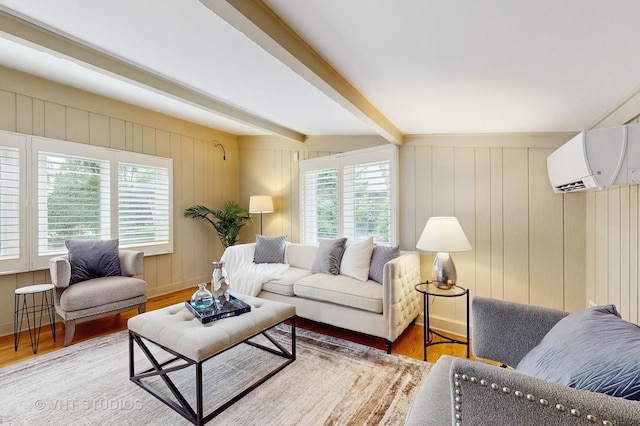 living area featuring baseboards, a wall mounted air conditioner, wood finished floors, and beam ceiling