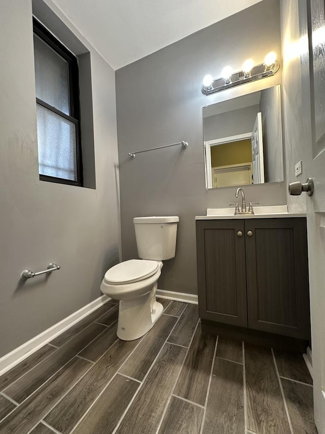bathroom with wood tiled floor, vanity, toilet, and baseboards