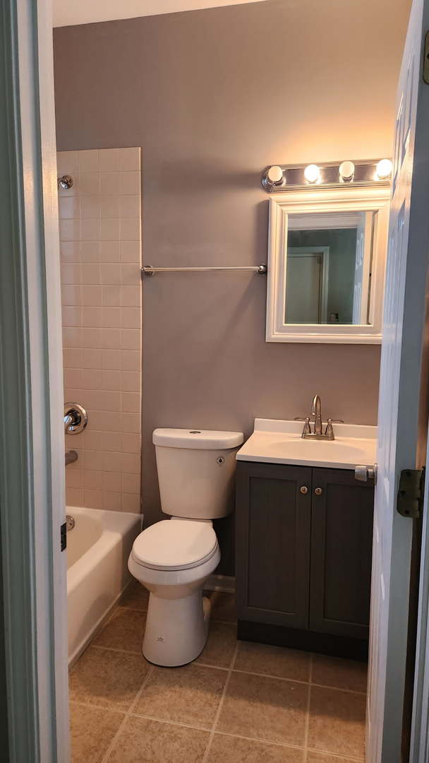 full bath featuring shower / bath combination, vanity, tile patterned flooring, and toilet