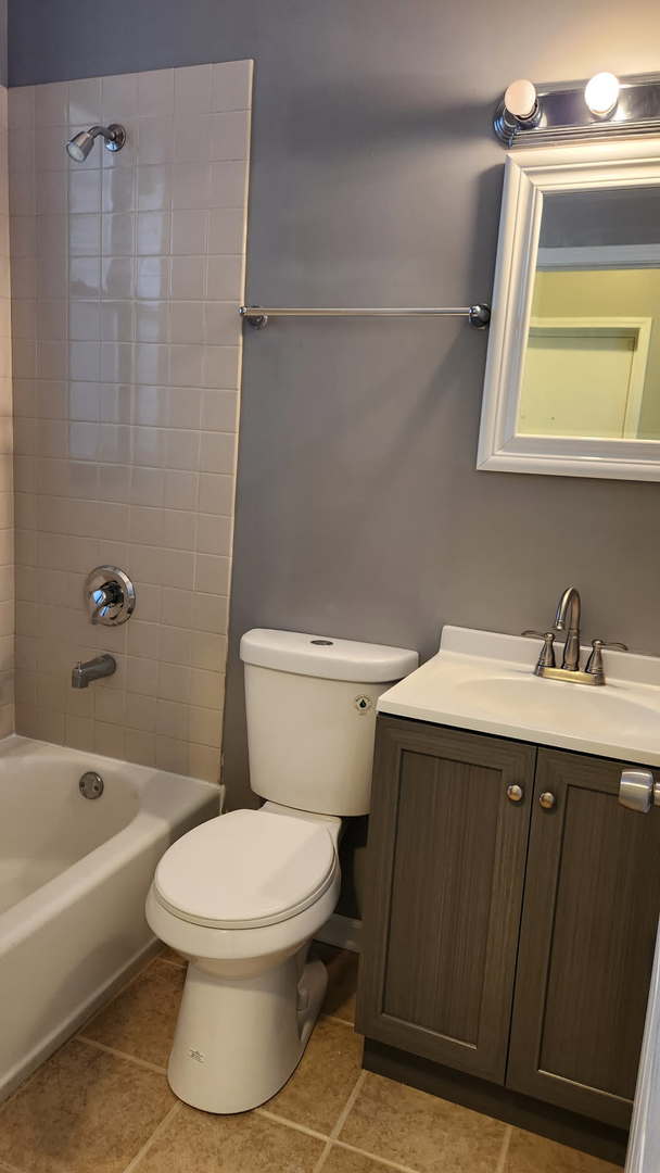 full bath featuring shower / bath combination, tile patterned flooring, vanity, and toilet