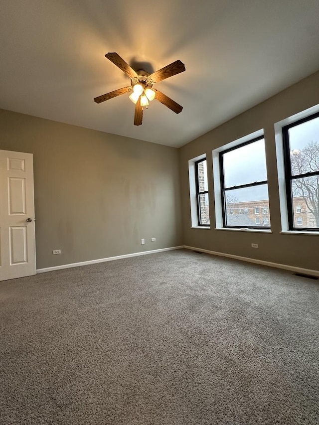 carpeted empty room featuring visible vents, baseboards, and ceiling fan