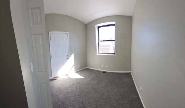 unfurnished room featuring lofted ceiling, dark colored carpet, and baseboards