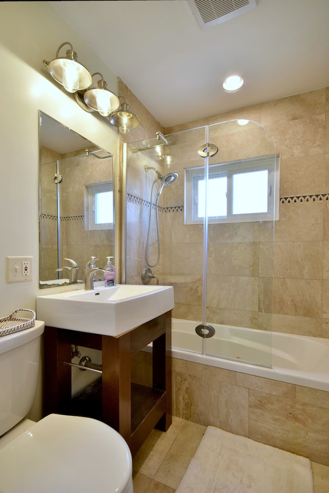 bathroom featuring visible vents, toilet, vanity, and tiled shower / bath
