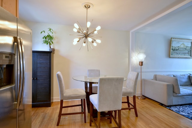 dining room with light wood finished floors, a notable chandelier, and baseboards