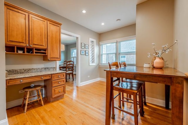 kitchen with light wood-type flooring, built in study area, and brown cabinets