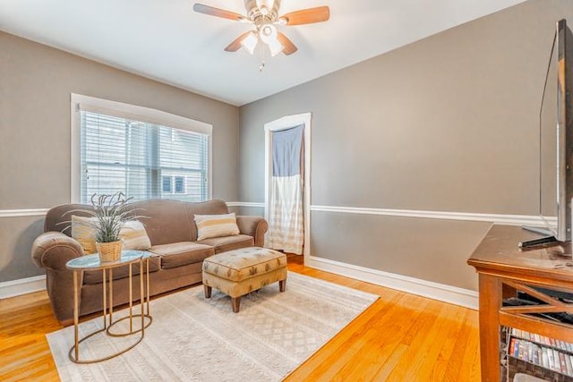 living area featuring baseboards, ceiling fan, and wood finished floors