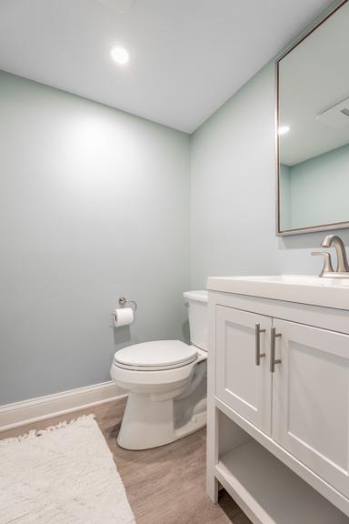 half bathroom featuring vanity, toilet, and wood finished floors