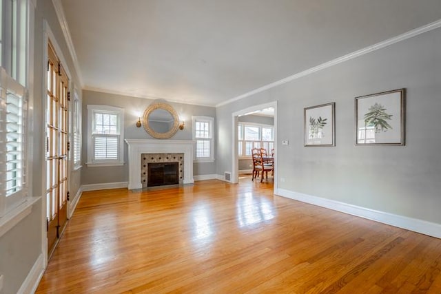 unfurnished living room with crown molding, baseboards, light wood finished floors, and a fireplace
