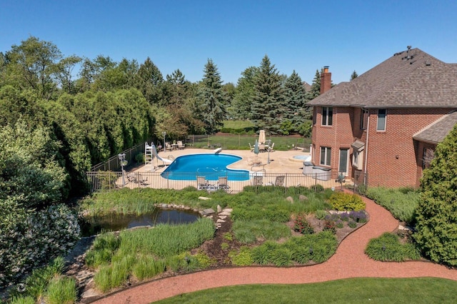 view of pool featuring a diving board, a water slide, a fenced backyard, a patio, and a fenced in pool