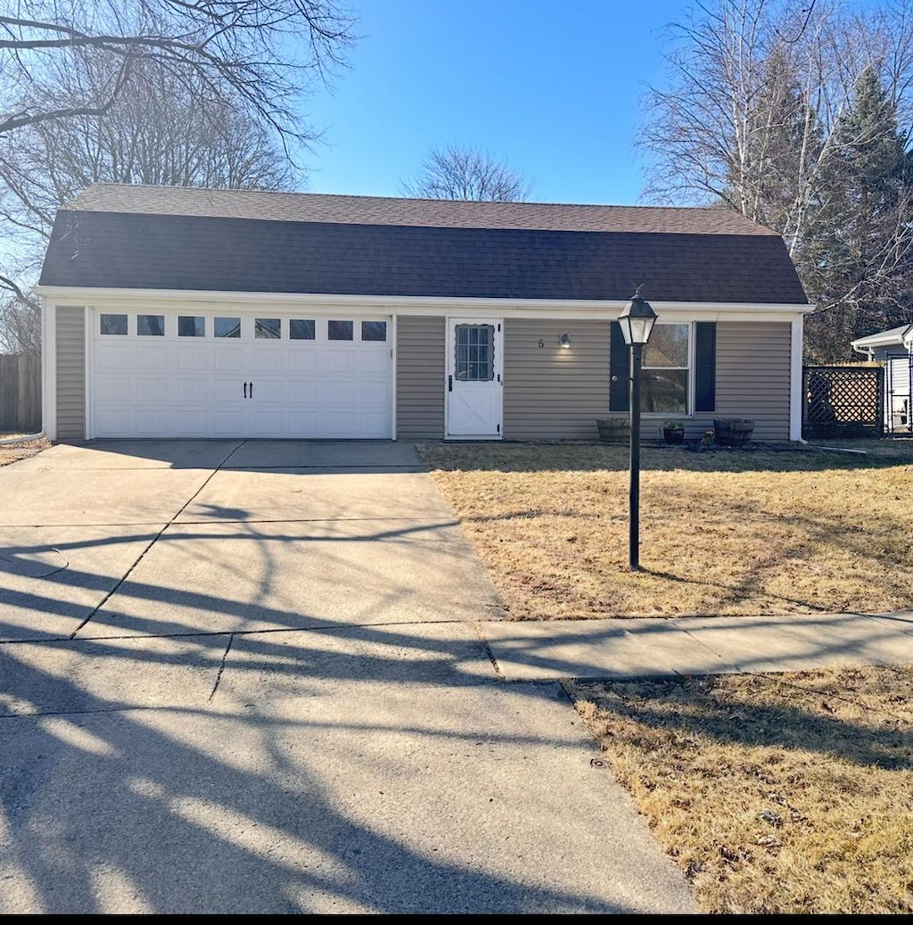 colonial inspired home with roof with shingles, concrete driveway, and an attached garage