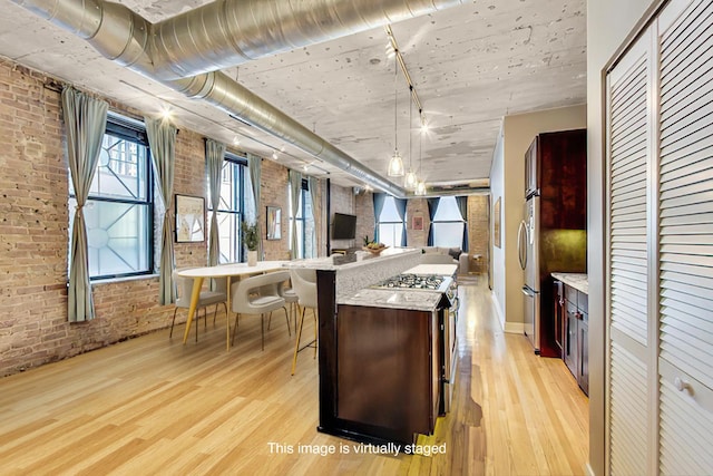 110 N Peoria St Unit 205, Chicago, IL 60607 - kitchen featuring brick wall, light wood-style floors, open floor plan, freestanding refrigerator, and a kitchen breakfast bar