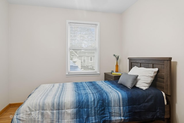 bedroom featuring multiple windows, baseboards, and wood finished floors