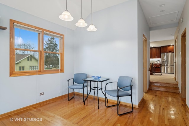living area featuring light wood-style floors, attic access, and baseboards