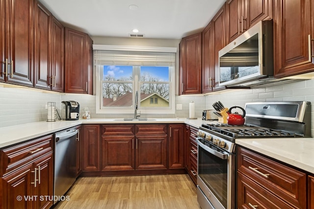 kitchen with visible vents, light countertops, a sink, stainless steel appliances, and backsplash