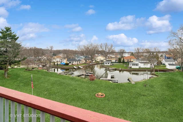 surrounding community with a water view, a boat dock, a residential view, and a lawn