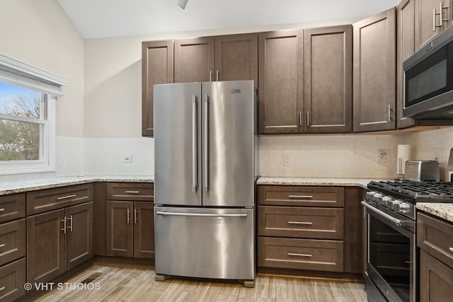 kitchen with light wood-style floors, appliances with stainless steel finishes, decorative backsplash, and dark brown cabinets