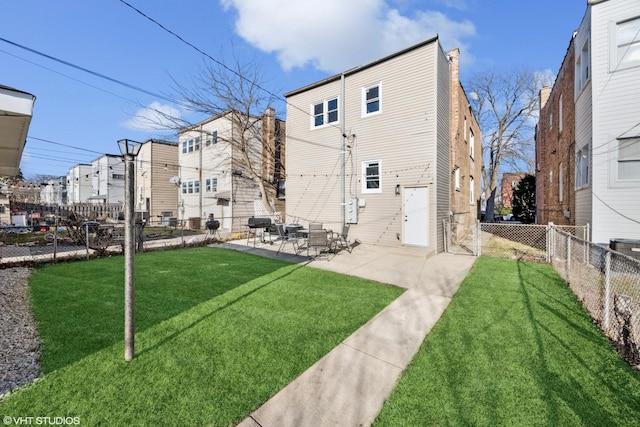 rear view of property featuring a yard, a fenced backyard, and a patio area